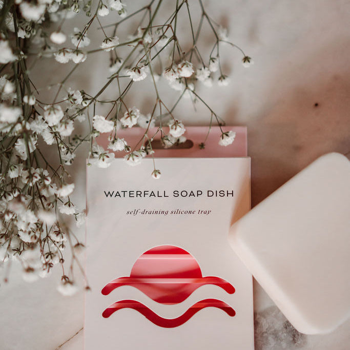 Earth Ahead soap dish with a bar of soap and white flowers on a marble surface