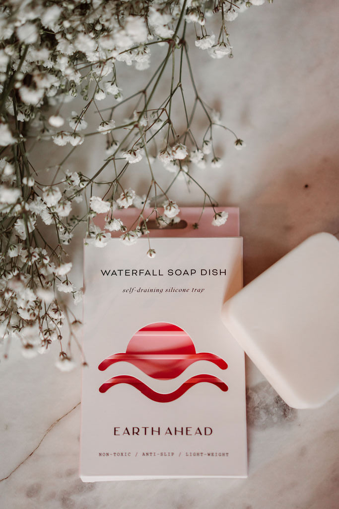 Earth Ahead soap dish with a bar of soap and white flowers on a marble surface