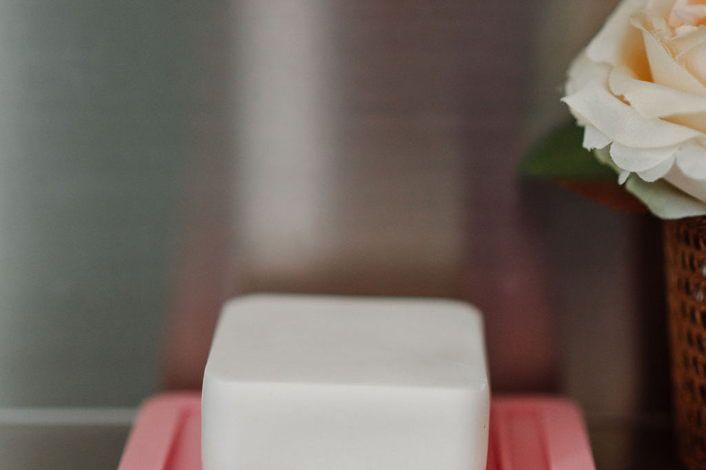 Bar of soap on a pink soap dish with a blurred background
