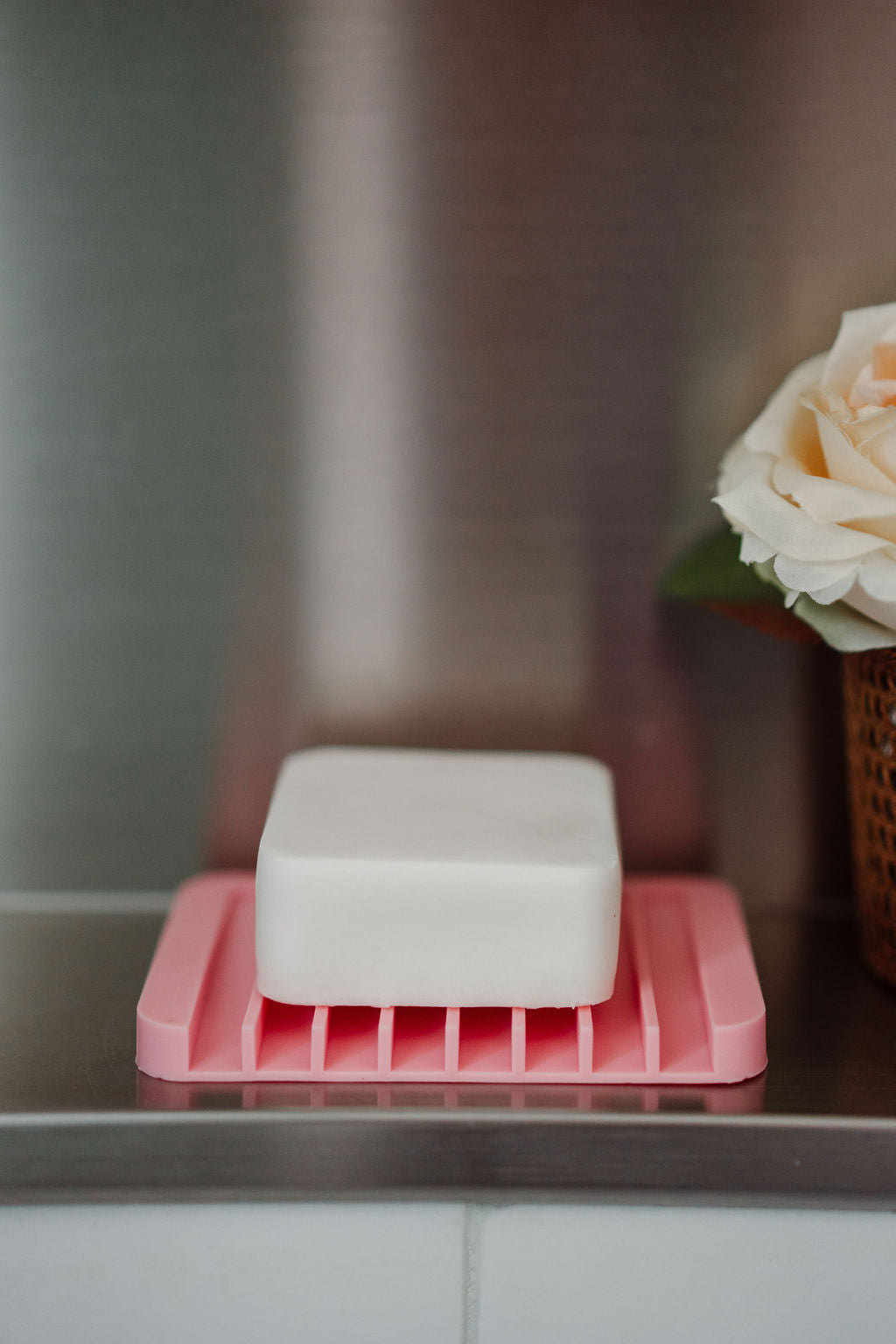 Bar of soap on a pink soap dish with a blurred background