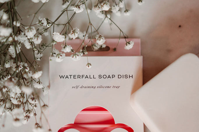 Earth Ahead soap dish with a bar of soap and white flowers on a marble surface
