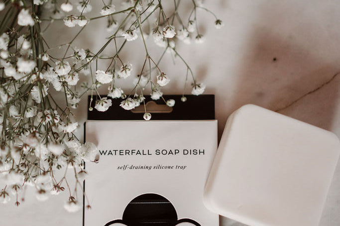 Earth Ahead soap dish with a bar of soap and white flowers on a marble surface